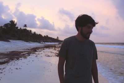 Man standing on beach against sky during sunset