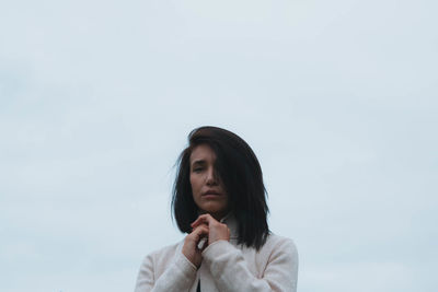 Portrait of young woman against clear sky