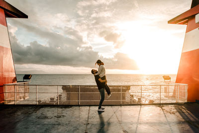 Couple hugging in a boat with a sunset in the background