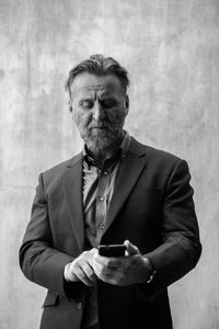 Mature man wearing suit standing against wall