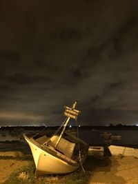 Sailboat moored on beach against sky at night