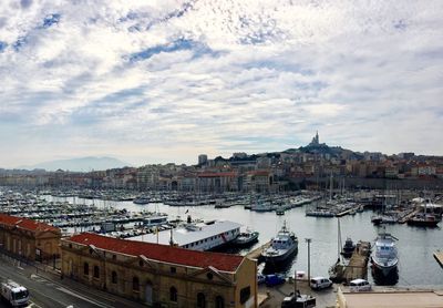 High angle view of boats moored at harbor against buildings in city