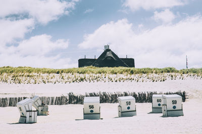 Hooded chairs at beach against sky