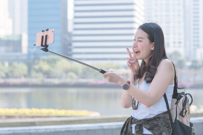 Young woman photographing with mobile phone in city