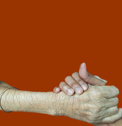 Close-up of hand against orange background