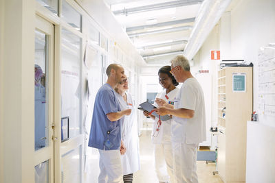 Smiling healthcare workers discussing while standing in corridor at hospital