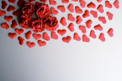 Directly above shot of heart shapes and artificial roses on white background