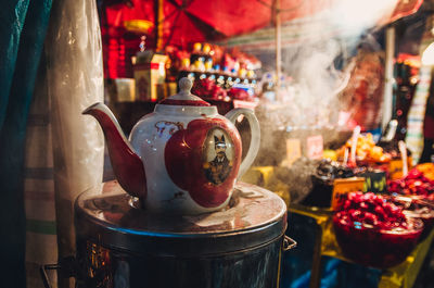 Close-up of kettle on table against market stall