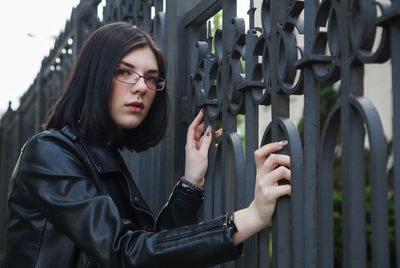 Portrait of young woman standing on metal structure