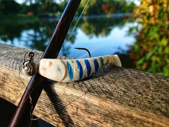 Close-up of fishing rod on railing against lake