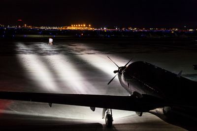 Airplane flying over illuminated city against sky at night