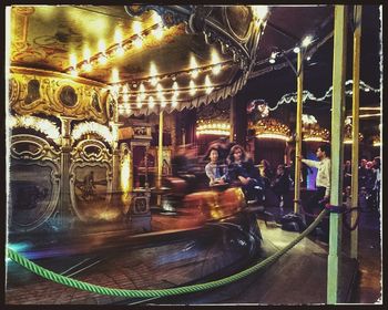 Side view of illuminated carousel at amusement park