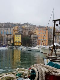 Boats moored at harbor in city against sky