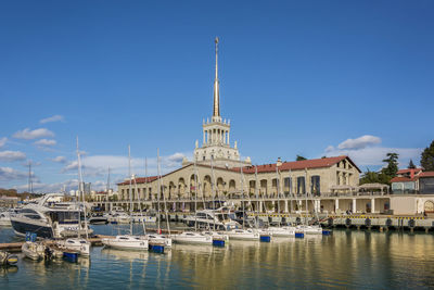 Boats moored at harbor against blue sky