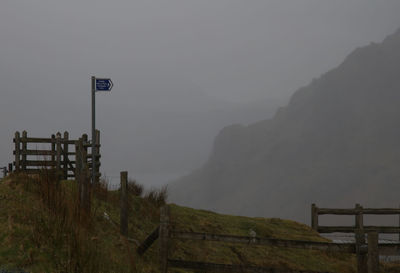 Road sign on field against sky