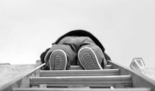 Low section of person resting on railing against sky