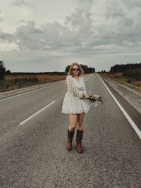 Portrait of woman standing on road against sky