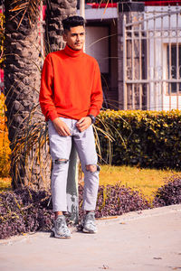 Portrait of young man standing on footpath