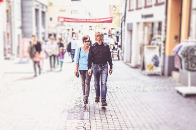 Rear view of friends walking on street in city