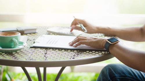 Midsection of man using mobile phone on table