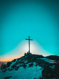 Cross on beach by building against clear blue sky