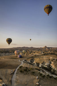 Hot air balloons flying over landscape against sky