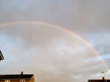 Low angle view of rainbow over building against sky