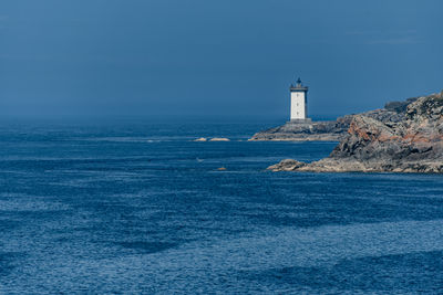 Lighthouse by sea against sky