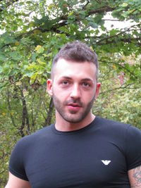 Portrait of young man standing against trees