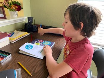 Portrait of boy sitting at table with book