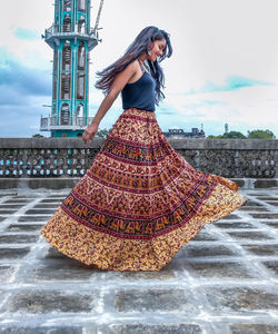 Side view of young woman wearing skirt while walking on footpath