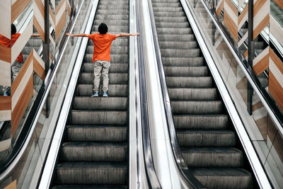 Rear view of boy standing on escalator