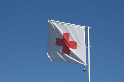 The flag of international red cross and red crescent movement against a blue sky in switzerland