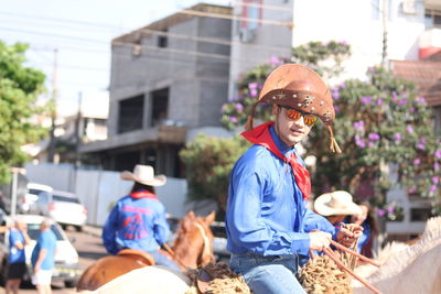 Portrait of cowboy riding horse in city