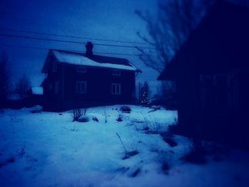 Snow covered houses against sky at night
