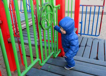 Cute toddler in a winter suit playing at the playground on the beach