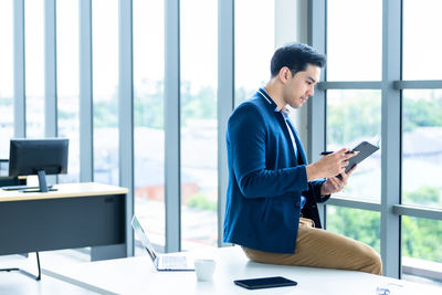 Businesswoman using digital tablet while standing in office