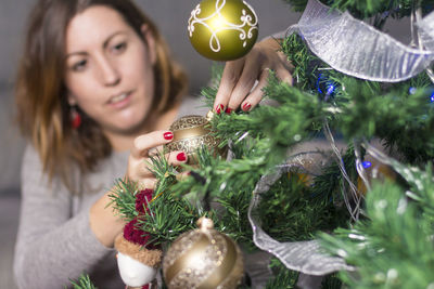 Woman decorating christmas tree at home