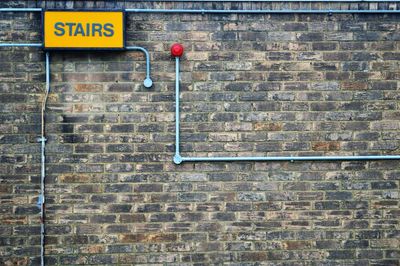 Stairs sign on brick wall with pipes