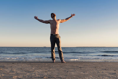 Full length of man standing at beach against clear sky