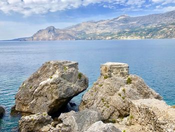 Rock formations by sea against sky