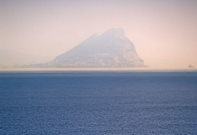 Scenic view of sea and mountains against clear sky