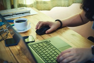 Cropped image of hand holding coffee cup on table