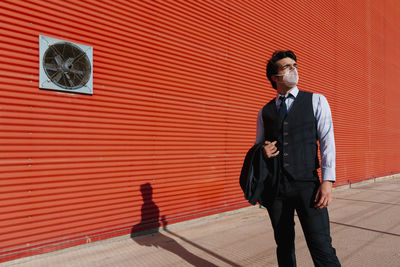 Full length of a young man standing against wall