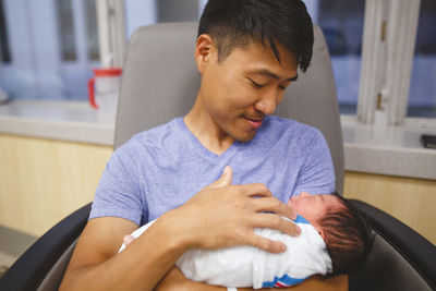 A proud new father gazes adoringly at his newborn daughter, cradling