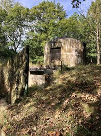 Old abandoned building by trees on field