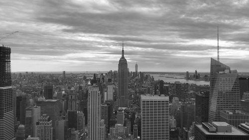 Aerial view of buildings in city against cloudy sky