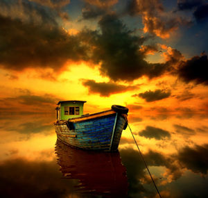 Low angle view of boat moored on beach against sky during sunset