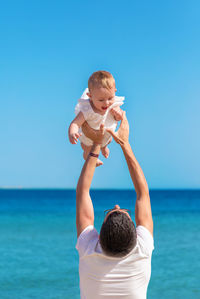 Side view of girl looking at sea against blue background