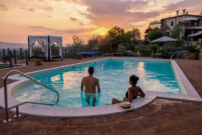 Rear view of couple in swimming pool against sky